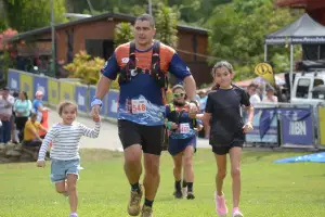 Padre corredor tomando de la mano a dos niños cerca de la meta