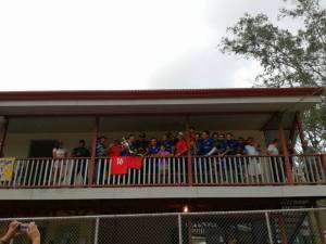 Equipo de futbol celebrando con un trofeo en el segundo piso de una casa