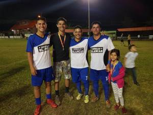 4 personas de un equipo de futbol y una niña posando en la noche