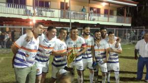 8 miembros de un equipo de futbol posando con trofeo
