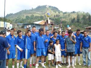 Equipo de futbol y dos niños posando con un trofeo alzado por un miembro